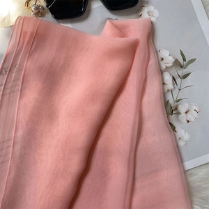 Detailed view of light pink silk scarf texture with elegant pearl accessories