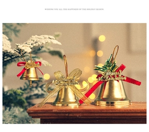 Golden Christmas bell ornaments with red and gold bows on a festive wooden surface