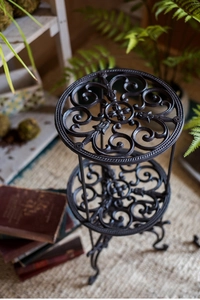 Détail d'un support de plante à deux étages en fonte avec des motifs en volutes