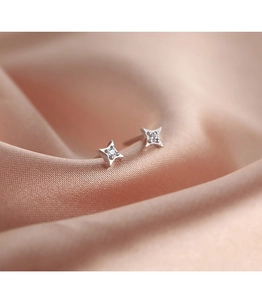 Macro shot of silver four-pointed star stud earring with a small sparkling zircon