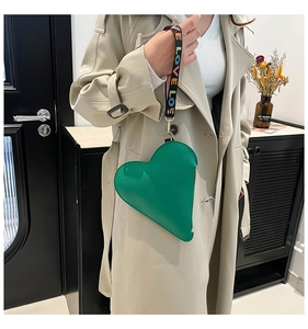 Detail of green heart-shaped bag with patterned LOVE strap and gold hardware
