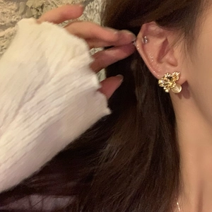 Detail of elegant gold flower earrings with white pearl drop on a female model
