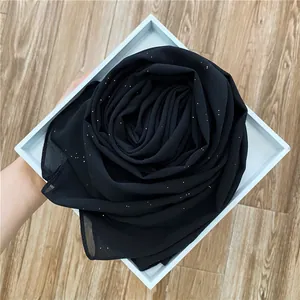 Détail d'un châle en mousseline noire avec paillettes dorées plié en forme de rose