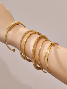 Close-up of stacked gold bamboo joint and spiral textured bangles on wrist