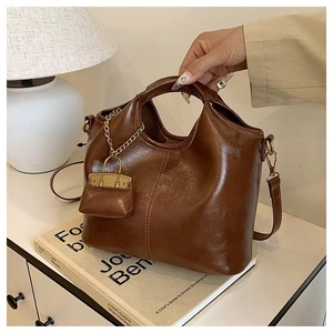 Detail view of brown oil wax leather tote bag with a matching mini pouch charm accessory