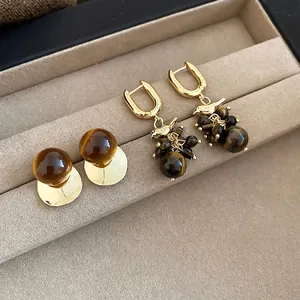18k gold-plated tiger eye bird tassel earrings shown on a jewelry display tray