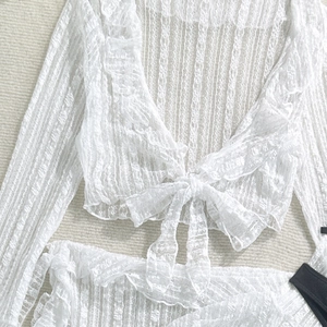 Detail of white semi-transparent lace swimwear featuring intricate striped floral patterns
