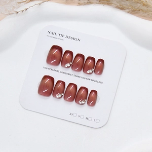 Handmade red cat eye press-on nails with rhinestones on a white display card