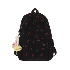 Détail d'un sac à dos en velours côtelé noir avec motif cerise et pendentif peluche