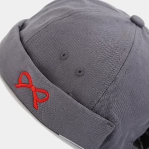 Close-up of red bow embroidery and fabric texture on gray cotton docker brimless hat