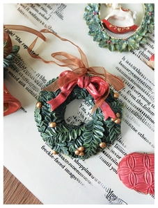 Macro shot of resin Christmas wreath ornament with red bow on retro paper background