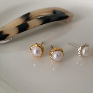 Detailed macro view of 8mm pearl earrings with handcrafted irregular gold and silver edges
