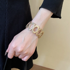 Close-up of hammered gold metal bracelet with overlapping oval links on wrist
