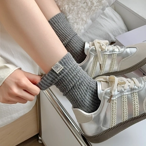 Detail of grey ribbed mid-calf socks featuring a dog print cloth label with silver sneakers