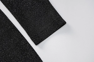 Detail of black knit fabric with sparkling silver threads and precise stitching on the hem