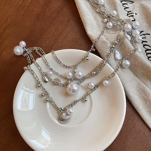 Detail of layered waist chain with pearls and shell charm on a white ceramic plate