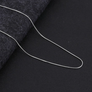 Macro close-up showing the fine texture and silver luster of a minimalist snake chain necklace