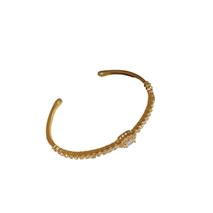 Gold plated oval zircon open bangle with pavé crystal accents on white background