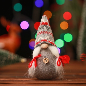 Close-up of a handmade grey knitted Christmas gnome with a red hat and white wooden button