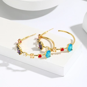 Chic gold C-shaped hoop earrings with colorful zircon stones on a white stand