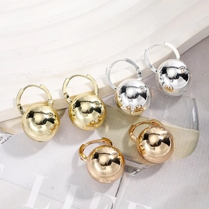 Polished metal ball earrings in gold, silver and rose gold on a geometric white display