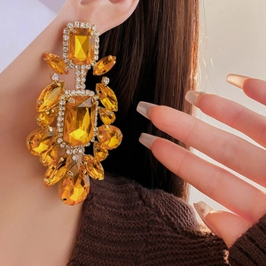 Detail showing oversized amber drop earrings with faceted gems and golden metal setting