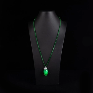 Dettaglio ciondolo a lampadina verde luminosa con catena di perle su busto nero
