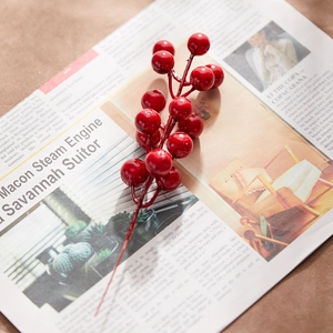 Artificial glossy red berry branches placed on newspaper for Christmas home decoration