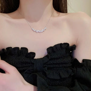 Close-up of silver-tone leaf necklace with zircon inlay on model's neckline