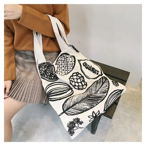Dettaglio di una grande borsa tote in tela bianca con stampe botaniche e frutti neri