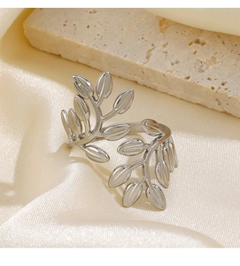 Macro shot of silver olive leaf ring with detailed vein textures on silk and stone