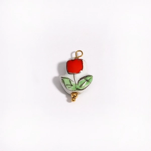 Detailed shot of tulip-shaped ceramic pendant with red flower and green leaves on gold loop
