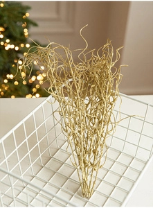 Close-up of glittery gold Christmas branch decoration in a white metal basket
