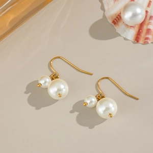 Boucles d'oreilles vintage en perles dorées avec pendentif double perle sur beige