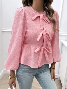 Detail of pink plaid women's top with three decorative bows and puff sleeve texture