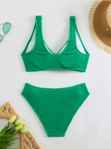 Flat lay of green textured bikini set with straw hat and sunglasses for summer vacation