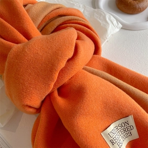 Detail of the woven label on an orange cashmere-like scarf with minimalist design texture
