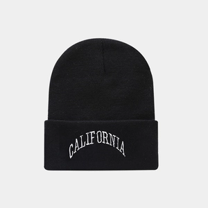 Detail of black knit beanie featuring white curved California embroidered lettering