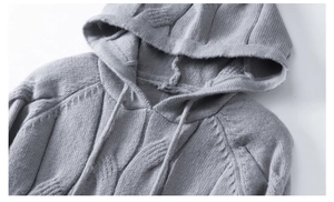 Detail of grey cable knit hoodie showing the drawstring hood and thick fabric texture