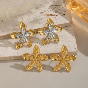 Detailed view of 18K gold and silver two-tone flower earrings on a textured stone surface