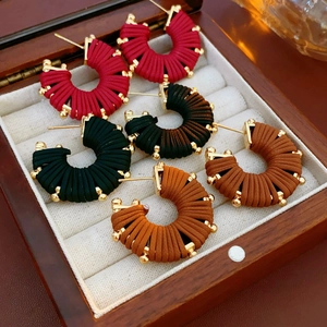 Detailed view of bohemian C-shaped earrings in red, black, and brown faux leather weave