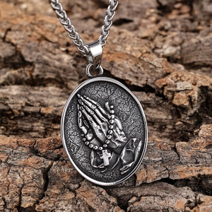 Vintage stainless steel oval pendant with praying hands and cross on tree bark background