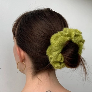 Macro detail of green crochet ruffle hair scrunchie styled on a bun hairstyle