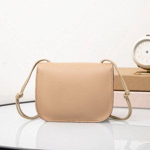 Close-up of khaki leather flap crossbody bag with drawstring strap on a cozy desk setting
