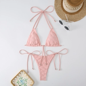 Flat lay of pink halter bikini set with checkerboard texture and beach accessories