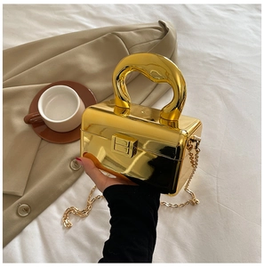 Detailed view of glossy gold metallic acrylic box bag with bold handle and chain strap