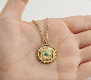 Detail of 18k gold necklace with turquoise gemstone in a sunburst pendant design