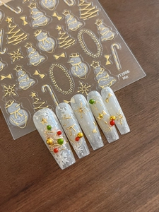 Detail view of gold 3D embossed Christmas nail stickers with snowman and tree patterns