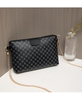 Detail of black PU leather crossbody bag with round floral print and gold chain strap