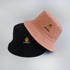 Detailed view of fine embroidery of yellow pineapple on black and orange bucket hats